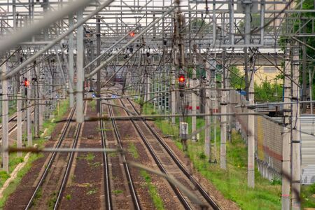Empty railroad tracks, metal structures above them with glowing red and blue light traffic lights,...