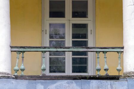 Vintage wooden railing with broken vertical wood carvings with remains of green paint between two columns in an abandoned manorの写真素材