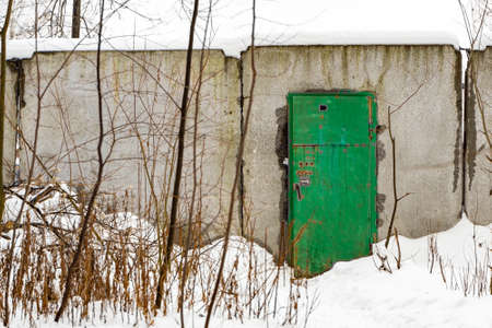 Open green metal door with combination lock in a concrete fenceの写真素材