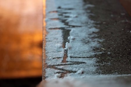 A line in the snow in the form of a cardiogram with a straight section. Granite slab. Cold and warm...