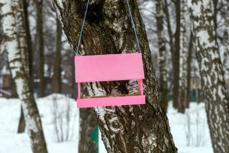 The pale pink bird feeder is suspended from a lilac rope. Wood. The park. Food.