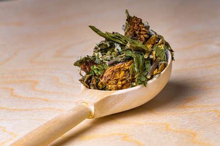 Assorted dry grass and plants in a wooden spoon on a flat board