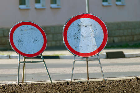 Two portable round old "No traffic" signs stand side by side on stands near the roadの写真素材