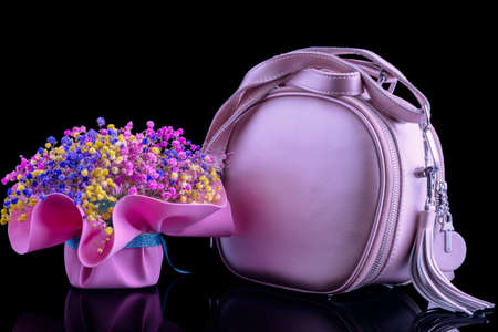Ladies pink bag next to a bouquet of flowers in pink tonesの写真素材
