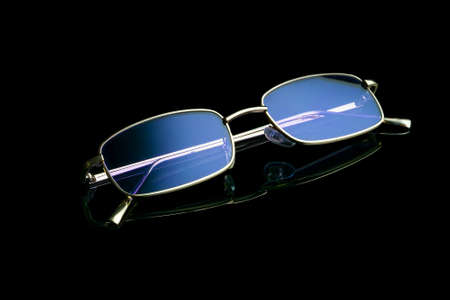 Sunglasses with purple glasses and a golden frame on a black background. With reflection.の写真素材