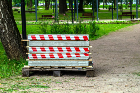 Concrete slabs are covered with a wooden pallet and wrapped with restrictive tape. In the park on the path for people. Compliance with security requirements.の写真素材
