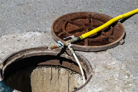 The hose of yellow color for washing the waterways is lowered into the well. Work to prepare water...