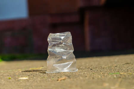 The crumpled plate cup stands upside down on the asphalt. With traces of water. drops. heat....