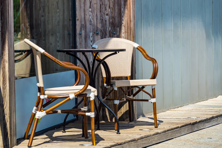 Two wooden wicker chairs and a table by the window near the wall of the cafe. outdoors. summer.の写真素材