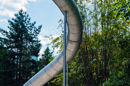 Curved metal pipe for children on poles. Against the background of the sky and greenery.の写真素材