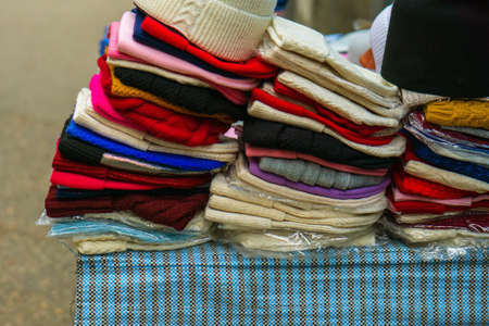 Women's knitted hats of different colors lie in stacks for sale on the street. Trading with hands.
