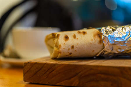 Shawarma, kebab in foil lies on a wooden baseの写真素材