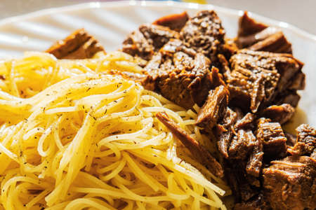 Pasta with pieces of beef meat sprinkled with spices in backlightの写真素材