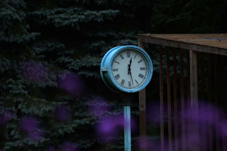 Street round clock with Roman numerals shows 28 minutes of the first.