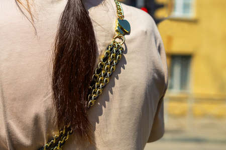 The back of a man with a strap from a bag in the form of a chain.