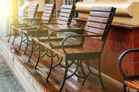 A number of chairs and tables made of wood are covered with drops of water.の写真素材