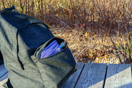 A dark-colored ryukaz on a wooden bench. A carandan, a pen and a brush stick out of your pocket. Autumn.の写真素材