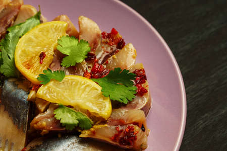 Herring fillet on a purple plate with spices, lemon, red pepper and herbs. On a dark wooden table.の写真素材