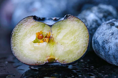 Macro. Cut blueberry berry with orange seeds inside. On a dark background.の写真素材