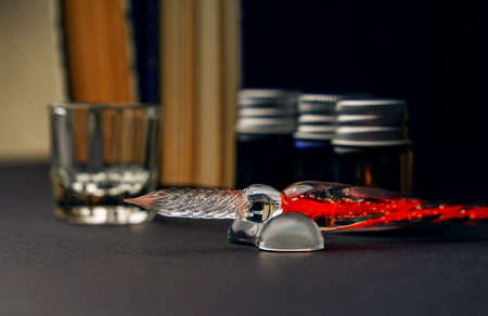 A plastic pen for calligraphy lies on a stand against the background of a container for ink and jars.の写真素材