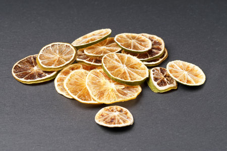 A pile of dried citrus slices. Lemon and lime. Against a dark background.の写真素材