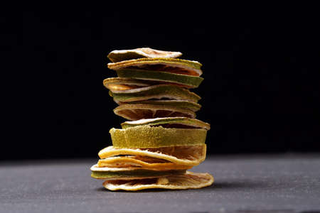 Slices of dried lemons and lime stacked in a column on a dark background.の写真素材