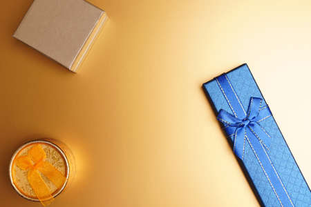 Boxes of gifts of small size and different shapes stand on a golden surface. View from aboveの写真素材