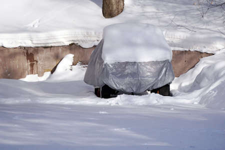 The car is covered with a protective cover on top of a lot of snow.の写真素材