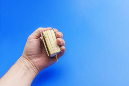 A hand holds a small book in its fist. The concept of knowledge in the handの写真素材
