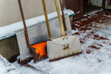 Shovels and scrapers for snow removal stand near the wallの写真素材