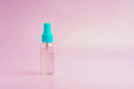 Transparent spray bottle filled with clear liquid on a pink backgroundの写真素材