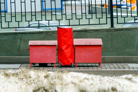 Red metal boxes of sand and a large fire extinguisher in a cover stand on the sidewalk near the gas station.の写真素材