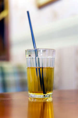 Apple juice in a faceted glass with a black straw on the table.の写真素材