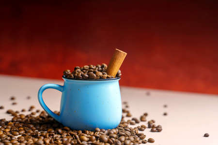 Blue ceramic mug filled with coffee beans and cinnamon stickの写真素材