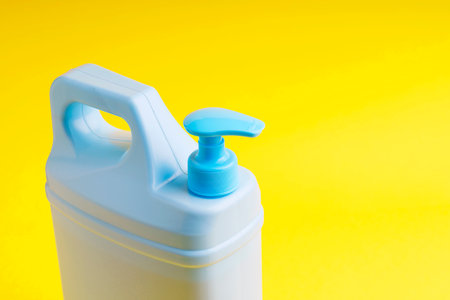 Plastic canister with antiseptic and dispenser view from above on a yellow background.の写真素材