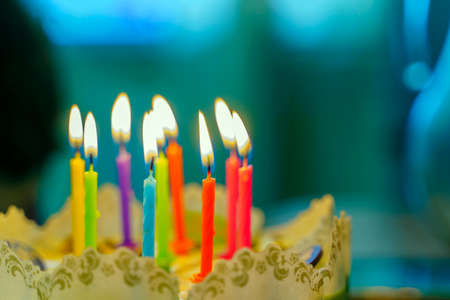 Nine colorful burning candles on a festive cake.の写真素材