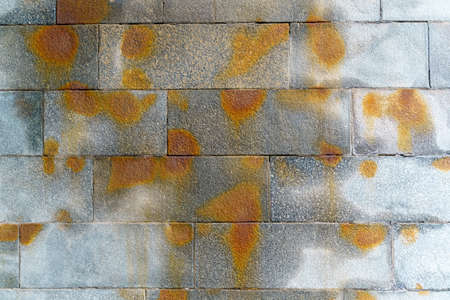 texture. Granite block wall with water streaks and orange spots.