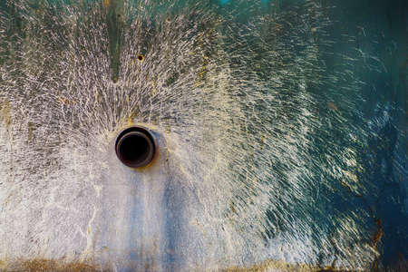 Live spray of white paint on the wall with the pipe cut off