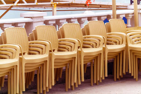 Rows of plastic chairs from a street restaurant stand on top of each other.の写真素材