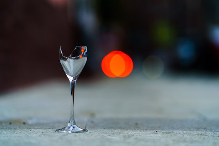 The concept of the evening party is over. A broken glass of wine against the red lights of a departing carの写真素材