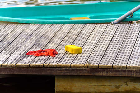 Sponge and rag lie on a wooden pier near boatsの写真素材