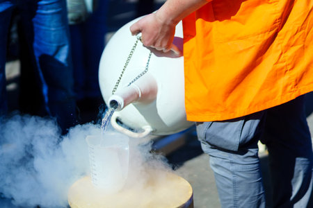 A person pours liquid nitrogen from a special container into a plastic mugの写真素材