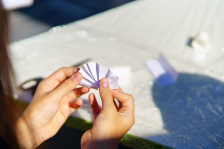The hands of a child who makes a figure out of paperの写真素材
