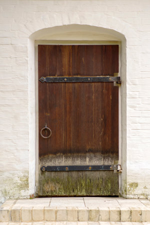 Old wooden door with round handle in a white brick wallの写真素材