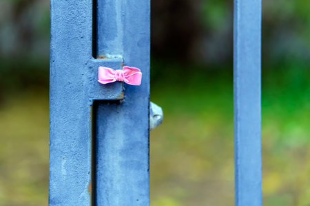 Small pink bow made of ribbon on a metal poleの写真素材