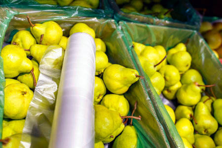 A roll of cellophane bags is in a box with pears in the storeの写真素材
