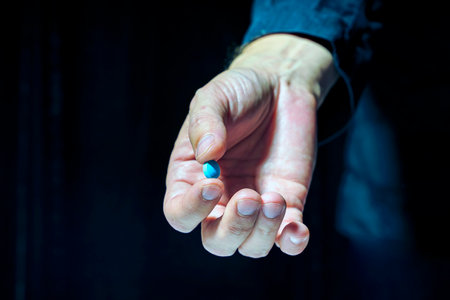 The hand of an old man holds a blue pillの写真素材