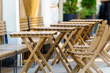Folding tables and chairs made of wood stand on the sidewalkの写真素材