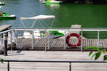 Lifebuoy on a wooden pier near a pond with catamaransの写真素材