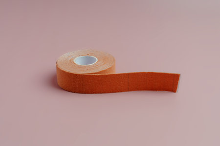 A roll of flesh-colored cosmetic ribbon on a pink backgroundの写真素材